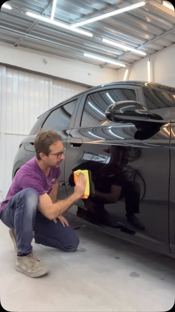 Marcelo, da Arte eu Acho, polindo um carro preto na oficina